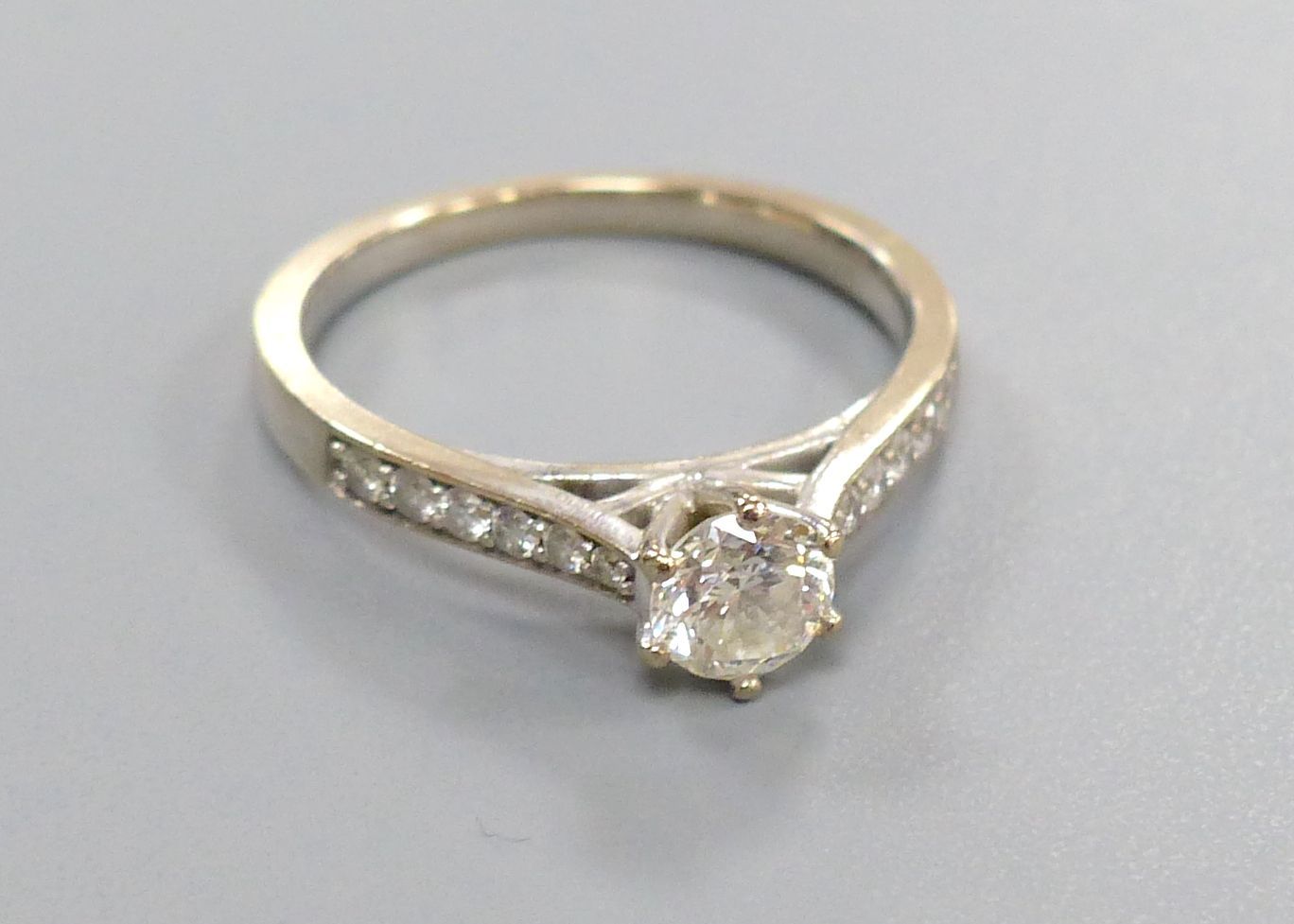 A diamond solitaire ring with diamond-set shoulders, 18ct white gold setting, size L, gross 3.2 grams.